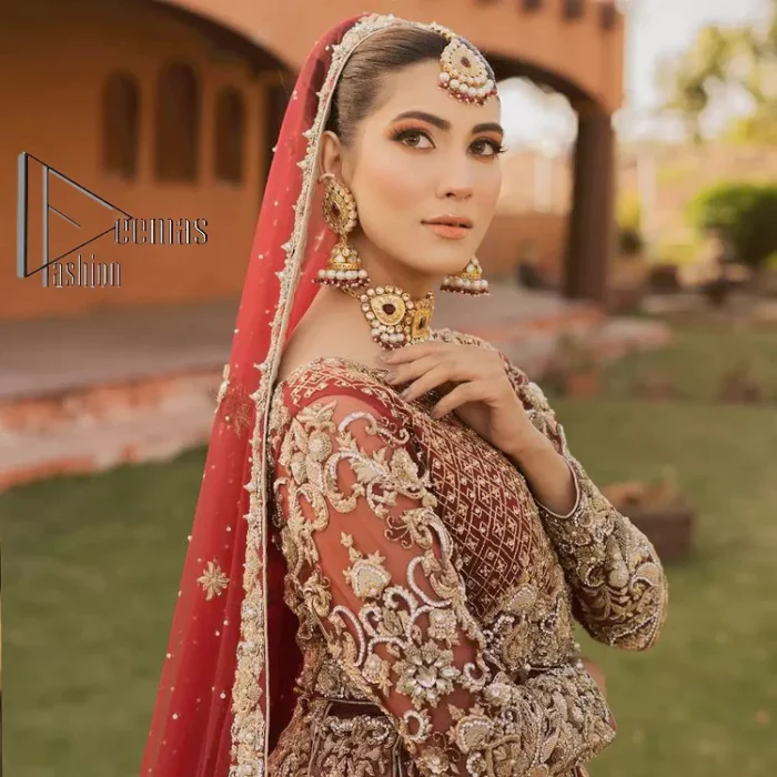 Love is in the air. A maroon blouse in maroon colour is hand-rendered in gold and is enhanced with naqshi, tilla, dabka, and kora along with the magic of zardozi. The boat shape neckline of the following blouse is pleasing to the outfit when combined with full sleeves to make your reception day more memorable. The flared lehenga in the same colours has gorgeous embroidery patterns and is paired up with a dupatta which is framed with a four-sided embellished border. It is further prominent with a sequin spray to give you the look of a model of the era.