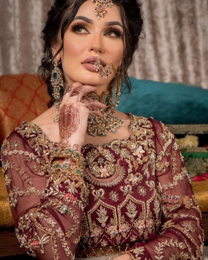 Take your style up a few notches in this elegant reception piece. A pure organza maroon fluffy lehnga is beautifully hand-rendered with golden embroidery and enhanced with  tilla, sitara, pearls, dabka and zardozi work. It is paired up with a blouse choli with tilla motifs on the full sleeves along with boat shape neckline to make your Big day astonishing and remarkable. The ivory organza dupatta has a four-sided embroidery adorned with pearls and Sitara and is framed with a scalloped style.