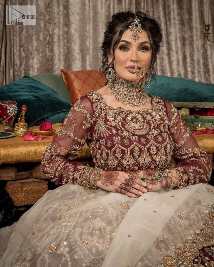 Take your style up a few notches in this elegant reception piece. A pure organza maroon fluffy lehnga is beautifully hand-rendered with golden embroidery and enhanced with  tilla, sitara, pearls, dabka and zardozi work. It is paired up with a blouse choli with tilla motifs on the full sleeves along with boat shape neckline to make your Big day astonishing and remarkable. The ivory organza dupatta has a four-sided embroidery adorned with pearls and Sitara and is framed with a scalloped style.
