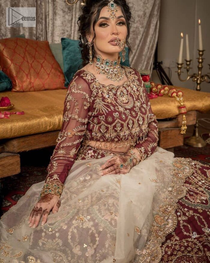 Take your style up a few notches in this elegant reception piece. A pure organza maroon fluffy lehnga is beautifully hand-rendered with golden embroidery and enhanced with  tilla, sitara, pearls, dabka and zardozi work. It is paired up with a blouse choli with tilla motifs on the full sleeves along with boat shape neckline to make your Big day astonishing and remarkable. The ivory organza dupatta has a four-sided embroidery adorned with pearls and Sitara and is framed with a scalloped style.