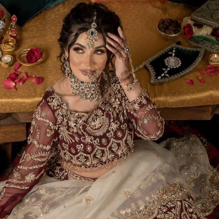 Take your style up a few notches in this elegant reception piece. A pure organza maroon fluffy lehnga is beautifully hand-rendered with golden embroidery and enhanced with  tilla, sitara, pearls, dabka and zardozi work. It is paired up with a blouse choli with tilla motifs on the full sleeves along with boat shape neckline to make your Big day astonishing and remarkable. The ivory organza dupatta has a four-sided embroidery adorned with pearls and Sitara and is framed with a scalloped style.