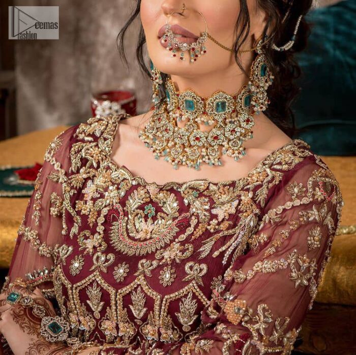 Take your style up a few notches in this elegant reception piece. A pure organza maroon fluffy lehnga is beautifully hand-rendered with golden embroidery and enhanced with  tilla, sitara, pearls, dabka and zardozi work. It is paired up with a blouse choli with tilla motifs on the full sleeves along with boat shape neckline to make your Big day astonishing and remarkable. The ivory organza dupatta has a four-sided embroidery adorned with pearls and Sitara and is framed with a scalloped style.