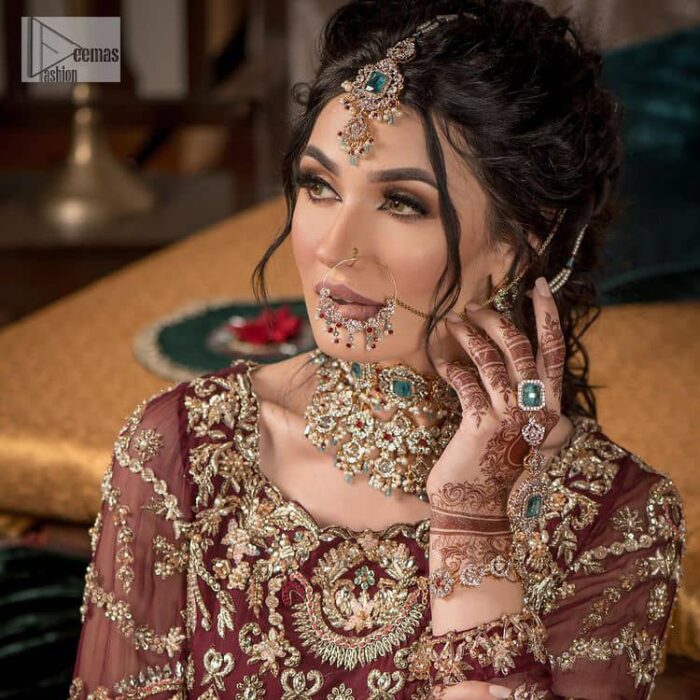 Take your style up a few notches in this elegant reception piece. A pure organza maroon fluffy lehnga is beautifully hand-rendered with golden embroidery and enhanced with  tilla, sitara, pearls, dabka and zardozi work. It is paired up with a blouse choli with tilla motifs on the full sleeves along with boat shape neckline to make your Big day astonishing and remarkable. The ivory organza dupatta has a four-sided embroidery adorned with pearls and Sitara and is framed with a scalloped style.