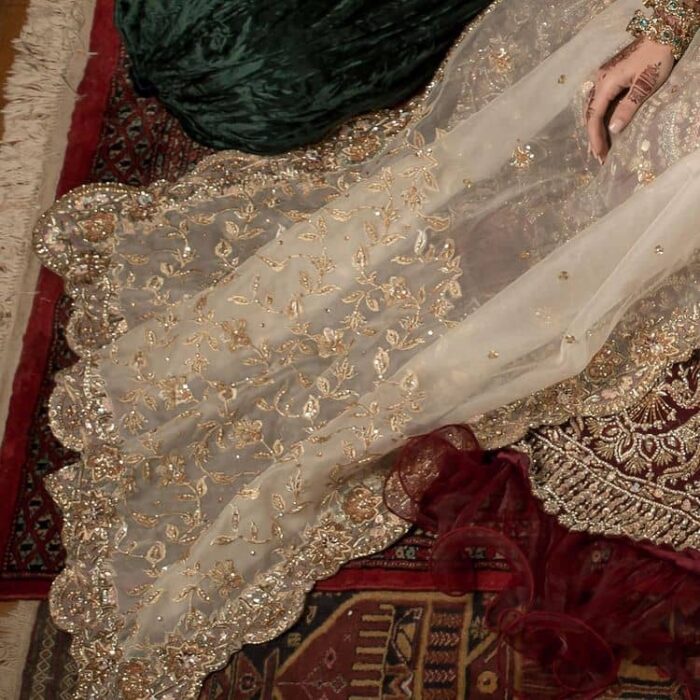 Take your style up a few notches in this elegant reception piece. A pure organza maroon fluffy lehnga is beautifully hand-rendered with golden embroidery and enhanced with  tilla, sitara, pearls, dabka and zardozi work. It is paired up with a blouse choli with tilla motifs on the full sleeves along with boat shape neckline to make your Big day astonishing and remarkable. The ivory organza dupatta has a four-sided embroidery adorned with pearls and Sitara and is framed with a scalloped style.