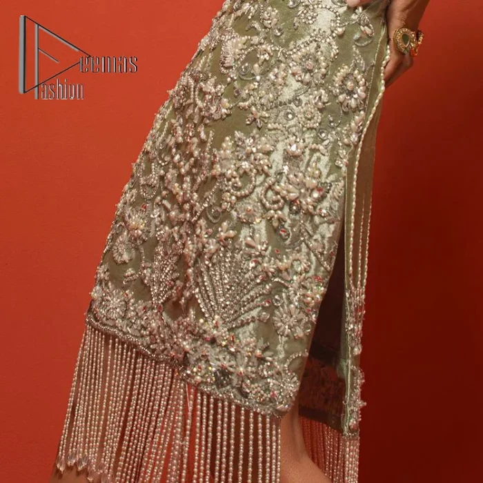 Celebrate your party events with DeemasFashion. An olive green shirt in tissue fabric, hand embellished with dabka, nakshi, cut dana, Resham, Swarovski, Mukesh, sequin and Kundan. A heavily embellished bodice featuring floral patterns all over to make your party event marvellous and shiny. The following heavy shirt is enhanced with V shape neckline along the sleeveless style. The bottom of the shirt has handsome fringes to give you a charming and splendid look.