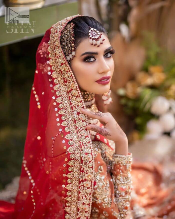 Shine bright in the sparkling ensemble from DeemasFashion. Introducing this reception outfit which begins with a rust pishwas.  This front en pishwas dipped in the richest shade of rust and is ornamented with golden embroidery which is further intensified with tilla, dabka, sequins and the real magic of zardozi. The strap neckline of the pishwas gives a unique aesthetic sense when comes with full sleeves. It is coordinated with an ivory lehenga whose border is embellished with golden embroidery. Finish this article with a dupatta framed with a four-sided embroidered border and sequin sprayed all over.