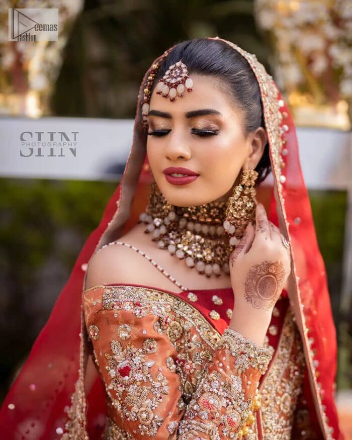 Shine bright in the sparkling ensemble from DeemasFashion. Introducing this reception outfit which begins with a rust pishwas.  This front en pishwas dipped in the richest shade of rust and is ornamented with golden embroidery which is further intensified with tilla, dabka, sequins and the real magic of zardozi. The strap neckline of the pishwas gives a unique aesthetic sense when comes with full sleeves. It is coordinated with an ivory lehenga whose border is embellished with golden embroidery. Finish this article with a dupatta framed with a four-sided embroidered border and sequin sprayed all over.