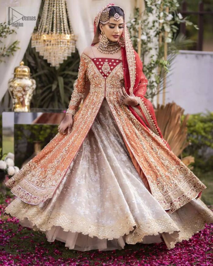 Shine bright in the sparkling ensemble from DeemasFashion. Introducing this reception outfit which begins with a rust pishwas.  This front en pishwas dipped in the richest shade of rust and is ornamented with golden embroidery which is further intensified with tilla, dabka, sequins and the real magic of zardozi. The strap neckline of the pishwas gives a unique aesthetic sense when comes with full sleeves. It is coordinated with an ivory lehenga whose border is embellished with golden embroidery. Finish this article with a dupatta framed with a four-sided embroidered border and sequin sprayed all over.
