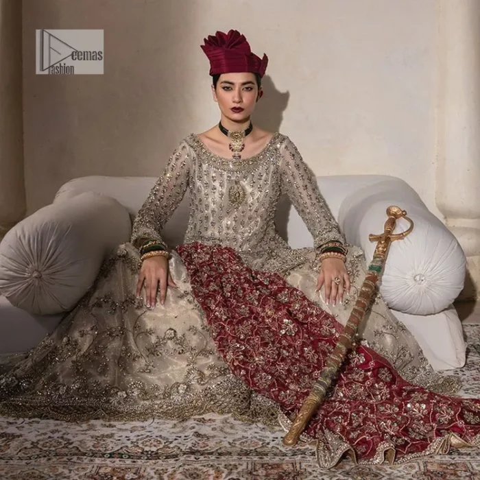 Unravel your inner density with our ivory nikah outfit. DeemasFashion presents this outfit which is embellished with light golden embroidery that further intensifies with tilla, dabka, kora, Kundan and the real magic of Zardozi. The ivory short shirt has boat shape neckline that is the epitome of royalty and grace. In addition to this, the embellished full sleeves also give a stunning touch to the shirt. It is coordinated with scalloped sharara making it a perfect choice to pair with the short shirt. Finish this outfit with a dupatta framed with four-sided embellished borders that gives you an impressive appearance on the Big day.