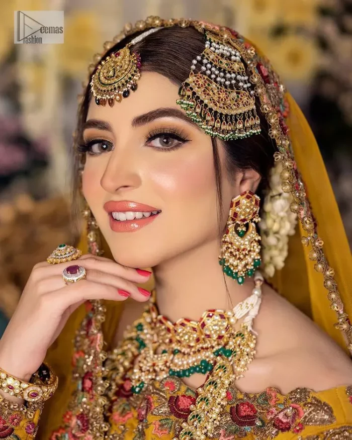Take your style quotient up a few notches in this exquisite mehndi outfit! ]The maxi in mustard colour is a ravishing bridal attire with a magnificent elite and classy appearance. Gorgeous and glamorous multiple-colour embroideries enhance the showiness of this maxi.  It is further intensified with tilla, dabka, kora, Kundan and details of thread embroidery. Full sleeves, boat shape neckline and sparkling work make it a perfect traditional wear. It is coordinated with a scalloped dupatta in the same colour which is embellished with four-sided borders and floral motifs all over to make this outfit unique and aesthetic.