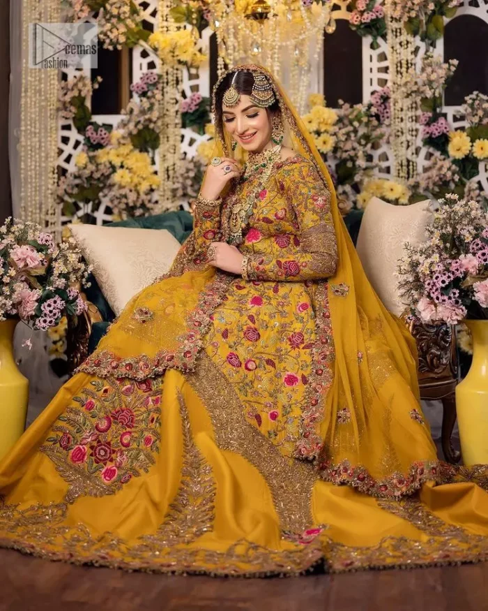 Take your style quotient up a few notches in this exquisite mehndi outfit! ]The maxi in mustard colour is a ravishing bridal attire with a magnificent elite and classy appearance. Gorgeous and glamorous multiple-colour embroideries enhance the showiness of this maxi.  It is further intensified with tilla, dabka, kora, Kundan and details of thread embroidery. Full sleeves, boat shape neckline and sparkling work make it a perfect traditional wear. It is coordinated with a scalloped dupatta in the same colour which is embellished with four-sided borders and floral motifs all over to make this outfit unique and aesthetic.