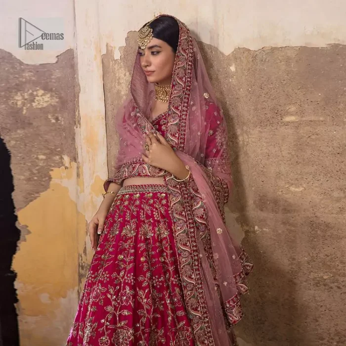 Blissful Pink! This ensemble is the epitome of grace. A shocking pink lehenga is heavily adorned with floral patterns. The flare of the lehenga gives a ravishing finishing look to this party wear. A beautiful blouse in the graceful shocking pink shade is an exquisite choice to pair with Lehenga. This choli is hand-embellished with lavish details of golden embroidery which is highlighted with dabka, tilla, kora, Kundan and details of Resham. Floral designs on half sleeves give a beautiful traditional touch to the masterpiece. It is paired up with a dupatta embellished with four-sided borders and tiny floral motifs all over.