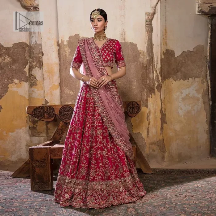 Blissful Pink! This ensemble is the epitome of grace. A shocking pink lehenga is heavily adorned with floral patterns. The flare of the lehenga gives a ravishing finishing look to this party wear. A beautiful blouse in the graceful shocking pink shade is an exquisite choice to pair with Lehenga. This choli is hand-embellished with lavish details of golden embroidery which is highlighted with dabka, tilla, kora, Kundan and details of Resham. Floral designs on half sleeves give a beautiful traditional touch to the masterpiece. It is paired up with a dupatta embellished with four-sided borders and tiny floral motifs all over.
