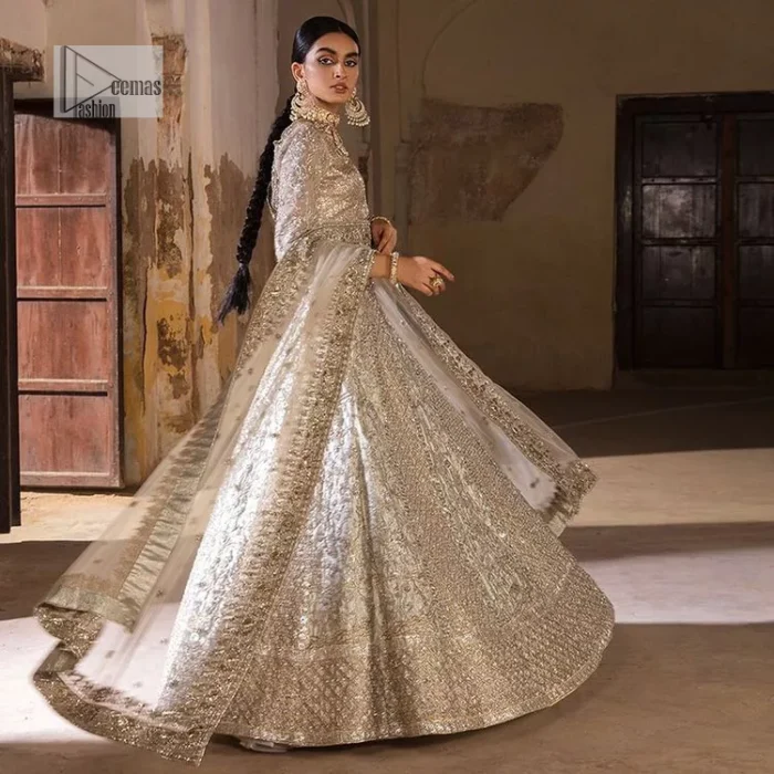 The fusion of this silver canvas decorated with vibrant contrasts is all you need to stun on your day! DeemasFashion presents this nikah wear in silver colour which is highlighted with tilla, dabka, kora, Kundan and the real magic of Zardozi. The round neckline of the following blouse has an ethnic charm. It is embellished with silver embroidery to make this masterpiece a dreamy one. The full sleeves style of the blouse also adds beauty to the outfit. It is paired up with a lehenga which is heavily embellished. The stunning dress in the Lehenga Choli style achieves the final charming look when paired with a dupatta in the same colour framed with four-sided borders and sequins sprayed all over. 
