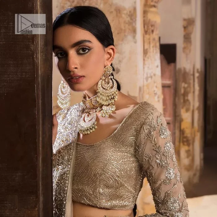 The fusion of this silver canvas decorated with vibrant contrasts is all you need to stun on your day! DeemasFashion presents this nikah wear in silver colour which is highlighted with tilla, dabka, kora, Kundan and the real magic of Zardozi. The round neckline of the following blouse has an ethnic charm. It is embellished with silver embroidery to make this masterpiece a dreamy one. The full sleeves style of the blouse also adds beauty to the outfit. It is paired up with a lehenga which is heavily embellished. The stunning dress in the Lehenga Choli style achieves the final charming look when paired with a dupatta in the same colour framed with four-sided borders and sequins sprayed all over. 