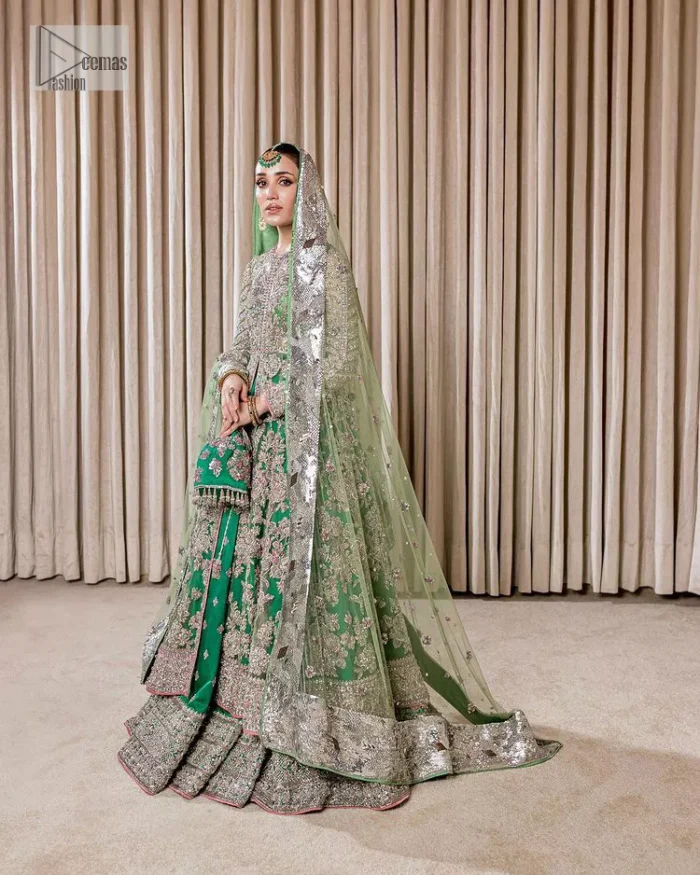 Dive into the world of ultimate allurement with this exquisitely embellished Mehndi outfit that depicts intricate glam with an elegant statement detailing. The maxi in teal green colour is heavily adorned with silver embroidery which involves tilla, dabka, kora, Kundan and the real magic of Zardozi. Further, the high neckline and full sleeves add extra glamour to this outfit. It is organized with magnificent lehenga in the same colour emblazoned with intricate gleaming embroidery which enhances the charm of this Dress. The tiny floral motifs also spread on the lehenga. Complete this article with a dupatta framed with four-sided borders and tiny floral motifs all over to make your day charming.