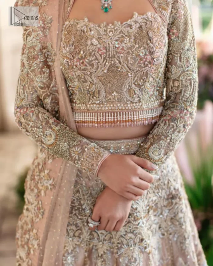 Trendy embroidery on a classic base – A perfect combination for your Nikah! DeemasFashion presents the tea rose article which is laboriously embellished with light golden embroidery which is further enhanced with tilla, dabka, kora, Kundan and beautiful details of Zardozi. The neckline is decorated with handsome embroidery. Further, the full sleeves of the blouse are unique in style and have a classy look and perfect choice for a bride. It is paired with flared lehenga which is heavily ornamented with embroidery to make your day memorable. Complete this article with a dupatta, framed with four-sided borders and sequins spray all over which is giving a charming finishing look to the dress.