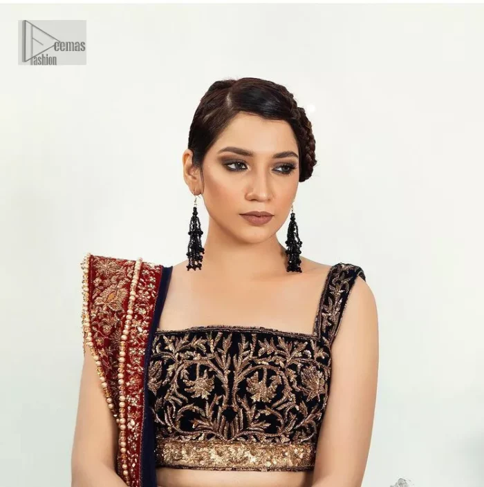 DeemasFashion presents this Party outfit which is an embellished masterpiece that wins everyone's hearts at the very first glance with its charm and elegance. The blouse in the oxford blue colour has laden with golden embroidery which makes this attire a head-turning masterpiece. Further, the square neckline is fully embellished with tilla, dabka, kora, Kundan, and pearls that is giving it a magical look. The strap neckline makes this outfit a little romantic but super charming. Paired up with a brocade lehenga which is embellished with a floral pattern to make your day. Complete this article with a dupatta, framed with a four-sided border.