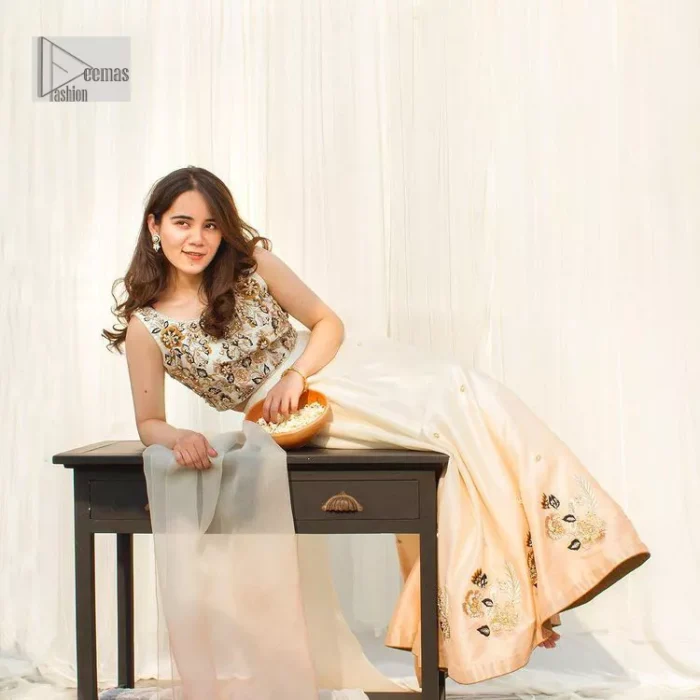 The fusion of this softest canvas decorated with vibrant contrasts is all you need to stun at any party! The embellished ivory article is the season’s most irresistible trend, the new-age lehenga blouse. The impeccably tailored choli has delicate multiple colour embroidery which intensifies with tilla, dabka, kora, Kundan and magic of Zardozi. The round neckline of the blouse is a beautifully crafted ensemble when combined with sleeveless style. The following blouse is paired with a double-tone can-can lehenga which is ornamented with embroidery on the border making it a perfect choice to pair with this masterpiece.