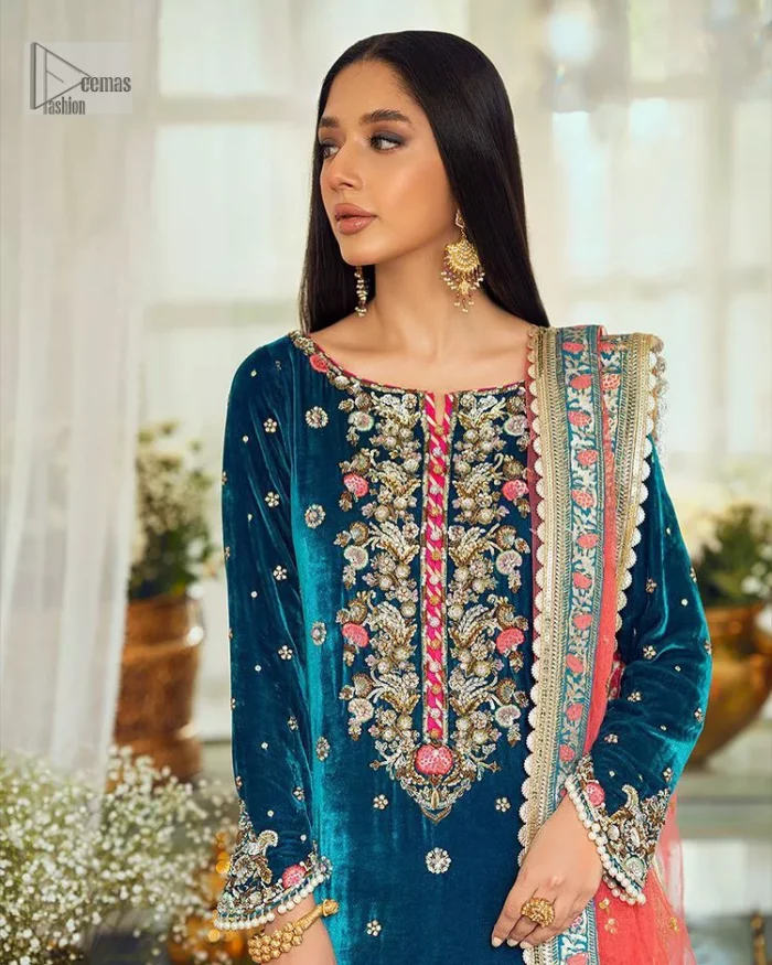 This dazzling yet elegant ensemble is perfect to make a statement at any event.  Long shirt for party dress in teal blue colour is embellished with multiple colour embroidery which is prominent with dabka, naqshi, stones, tilla, crystals work. The boat shape neckline is decorated with embroidery and with full-length sleeves. The fabric used for the shirt is velvet. It is paired with jamawar trousers in the same colour that is unique in style. Finish this party wear with a scalloped dupatta framed with a four-sided border and ting floral motifs all over that is the perfect choice for a party.