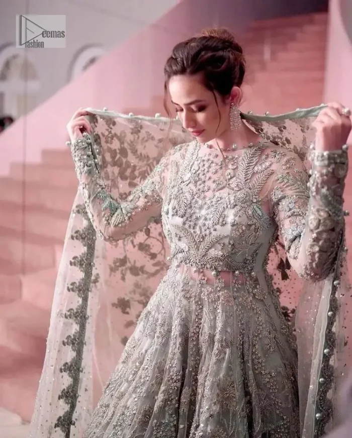 The magic reflects in every piece of this nikah wear. DeemasFashion presents a stunning outfit in an aqua-blue colour. A heavenly designed aqua blue maxi on an organza base serves as a canvas for spellbinding embellishments of gold, tilla, dabka, kora, Kundan and sequins. It is highlighted with silver embroidery to gain the spotlight of the show. The jewel neckline and full sleeves are rendered with beautiful floral patterns and embroidered borders. It is organized with a lehenga in the same colour, adorned with beautiful embroidery giving the perfect final touch. Complete this outfit with a dupatta in the same colour. This dupatta is adorned with floral motifs and silverwork. The embellished borders of this delicate net dupatta make this article your foremost priority.