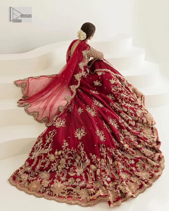 Be a dreamy vision in this reception wear. The beautiful pishwas in the bright red shade is embellished with intricate designs and fine details. It is enhanced with hand-crafted golden embroidery with details of tilla, dabka, kora, Kundan and magic of Zardozi. The round neckline and three-quarter sleeves feature a heavily crafted geometric pattern enhanced by cutwork detailing. The following front open scalloped pishwas is organized with a back train lehenga whose border is beautifully decorated with embroidery making it an epitome of beauty and grace. Furthermore, The embellished borders of the red scalloped dupatta give a perfectly glamorous look to the beautiful overall outfit. It is also intensified with sequins spray.