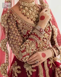 Be a dreamy vision in this reception wear. The beautiful pishwas in the bright red shade is embellished with intricate designs and fine details. It is enhanced with hand-crafted golden embroidery with details of tilla, dabka, kora, Kundan and magic of Zardozi. The round neckline and three-quarter sleeves feature a heavily crafted geometric pattern enhanced by cutwork detailing. The following front open scalloped pishwas is organized with a back train lehenga whose border is beautifully decorated with embroidery making it an epitome of beauty and grace. Furthermore, The embellished borders of the red scalloped dupatta give a perfectly glamorous look to the beautiful overall outfit. It is also intensified with sequins spray.
