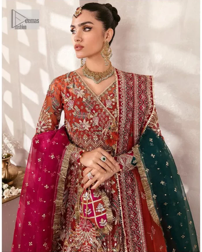 This deep rust outfit with a floral pattern has you covered for your big day. This deep rust angrakha is hand rendered in shades of multiple colours. The angrakha is decorated with gota, nakshi, dabka, and tilla in contrasting colours and is attached to hand-embellished panels. Further, the V shape neckline makes this masterpiece unique and priceless. The full sleeves of the following angrakha are a delightful way to add beauty to this mehndi wear. It is paired with a lehenga in the same colour having embroidered borders. Complete this traditional outfit with a dupatta in the green colour which is adorned with a four-sided Kiran and sequins sprayed all over.