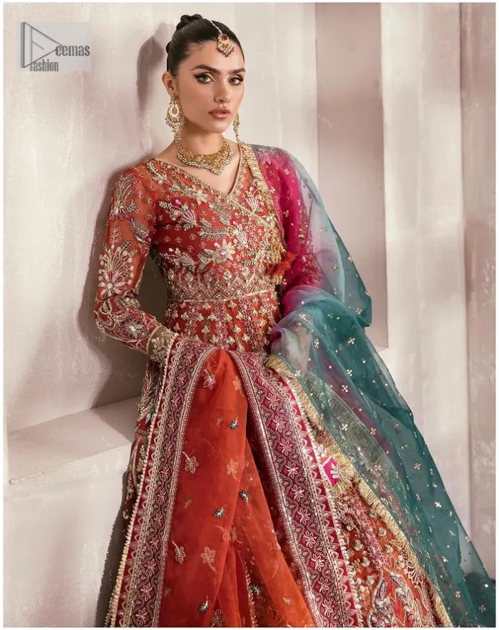 This deep rust outfit with a floral pattern has you covered for your big day. This deep rust angrakha is hand rendered in shades of multiple colours. The angrakha is decorated with gota, nakshi, dabka, and tilla in contrasting colours and is attached to hand-embellished panels. Further, the V shape neckline makes this masterpiece unique and priceless. The full sleeves of the following angrakha are a delightful way to add beauty to this mehndi wear. It is paired with a lehenga in the same colour having embroidered borders. Complete this traditional outfit with a dupatta in the green colour which is adorned with a four-sided Kiran and sequins sprayed all over.