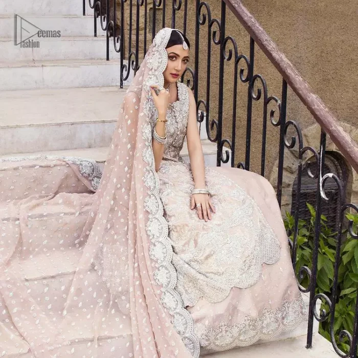 The subtle colour palette, delicate embroidery and eye-catching details. All in all a true style statement! Presenting this fawn maxi which is a luxuriously encrusted masterpiece is laden with tilla, dabka kora, stones,  and delicate Resham. The following front open scalloped maxi is adorned with silver embroidery to make your Nikah day remarkable. The embellished neckline along with the sleeveless style makes you a pretty and unique bride ever. Paired up this article with a sharara whose border is adorned with embroidery. Finish this outfit with a dupatta, framed with four-sided borders and sequins sprayed all over for attractiveness and marvellous details.