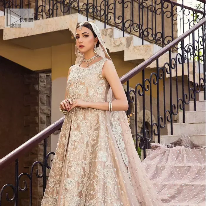 The subtle colour palette, delicate embroidery and eye-catching details. All in all a true style statement! Presenting this fawn maxi which is a luxuriously encrusted masterpiece is laden with tilla, dabka kora, stones,  and delicate Resham. The following front open scalloped maxi is adorned with silver embroidery to make your Nikah day remarkable. The embellished neckline along with the sleeveless style makes you a pretty and unique bride ever. Paired up this article with a sharara whose border is adorned with embroidery. Finish this outfit with a dupatta, framed with four-sided borders and sequins sprayed all over for attractiveness and marvellous details.
