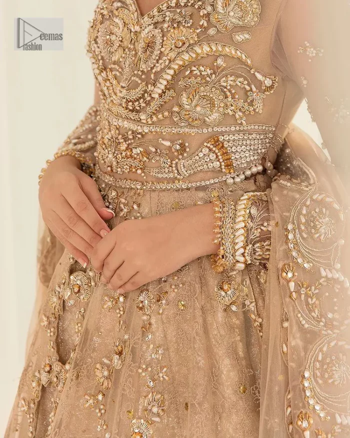 Presenting elegance personified glamorous formal nikah outfit. A heavenly-designed light golden maxi on an organza base serves as a canvas for spellbinding embellishments of antique gold, tilla, dabka, kora, Kundan and sequins. The sweetheart neckline makes this outfit unique and priceless. Furthermore, the following flawed maxi has three-quarter sleeves. It is paired with a plain lehenga and a dupatta in the same colour. The dupatta is adorned with carefully placed sequin spray and embellished four-sided borders for more calm and charm.