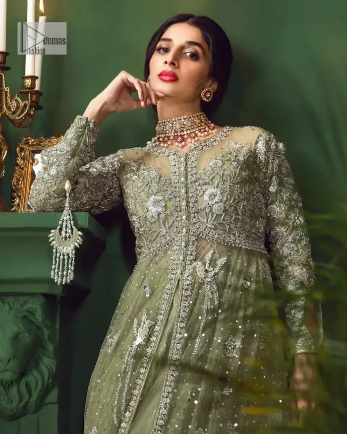 Experience the joy of a wedding in dreamy ensembles. Bringing old-world charm into your festive ensembles, it is a front open scalloped maxi intricately embellished with fine silver embroidery, crystals, tilla, dabka, kora and sequin. The full sleeves of the maxi make it an expression of timeless elegance. In addition to this, the V shape neckline makes this masterpiece unique and priceless. Paired with a long border embellished scalloped dupatta it all comes together to create a luxuriously chic look. The dupatta is also embellished with tiny floral motifs and sequins spray. Complete this party wear with a simple lehenga in the same colour to balance the overall look of the outfit.