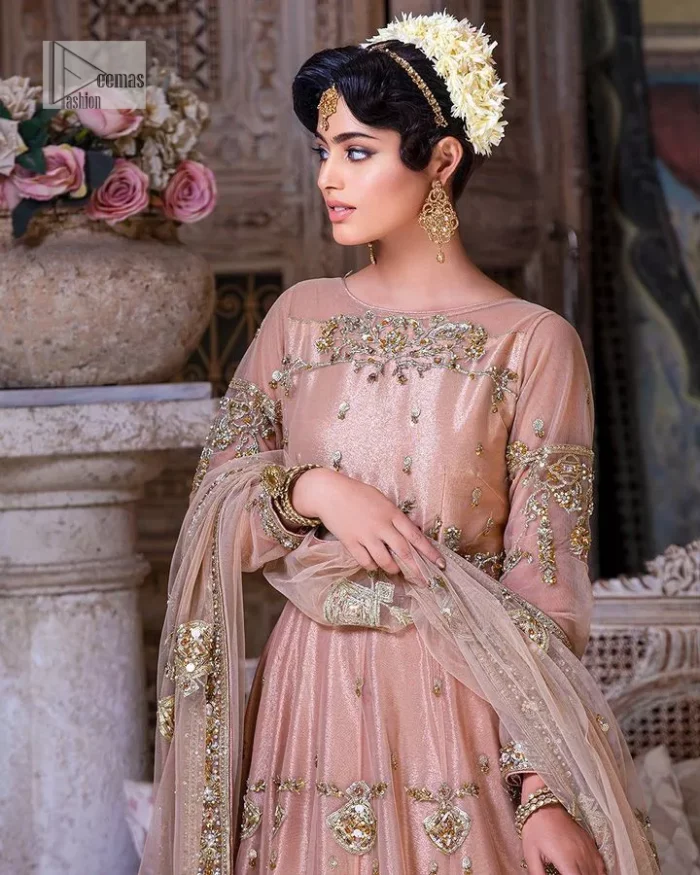 Wrap yourself in stunning style on your Big day. This tea-pink maxi dupatta is a stunning attire to wear at the wedding. This breathtaking nikah wear is gracefully adorned with hand-crafted embellishments and lavish golden work creating a magnificent masterpiece to give you your desired appearance. Intricate designs, floral details, naqshi, kora, Kundan, tilla and dabka o maxi enhance the overall charm of this beautiful outfit. The full sleeves of the maxi are highlighted with golden embroidery. Further, the boat shape neckline makes this outfit an epitome of beauty. It is systemized with a dupatta in the same colour adorned with four-sided borders and floral motifs all over.