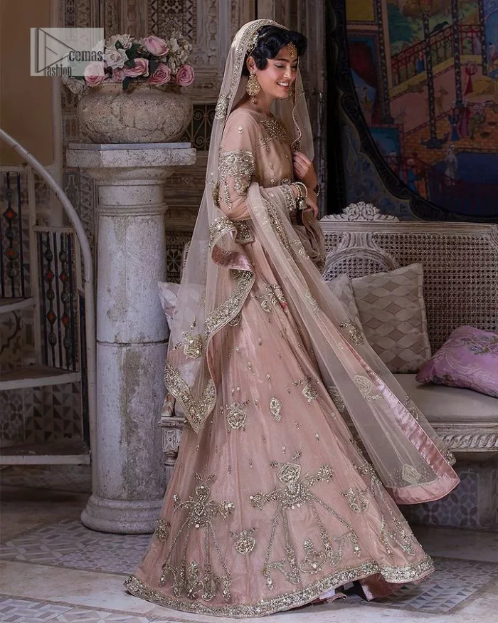 Wrap yourself in stunning style on your Big day. This tea-pink maxi dupatta is a stunning attire to wear at the wedding. This breathtaking nikah wear is gracefully adorned with hand-crafted embellishments and lavish golden work creating a magnificent masterpiece to give you your desired appearance. Intricate designs, floral details, naqshi, kora, Kundan, tilla and dabka o maxi enhance the overall charm of this beautiful outfit. The full sleeves of the maxi are highlighted with golden embroidery. Further, the boat shape neckline makes this outfit an epitome of beauty. It is systemized with a dupatta in the same colour adorned with four-sided borders and floral motifs all over.