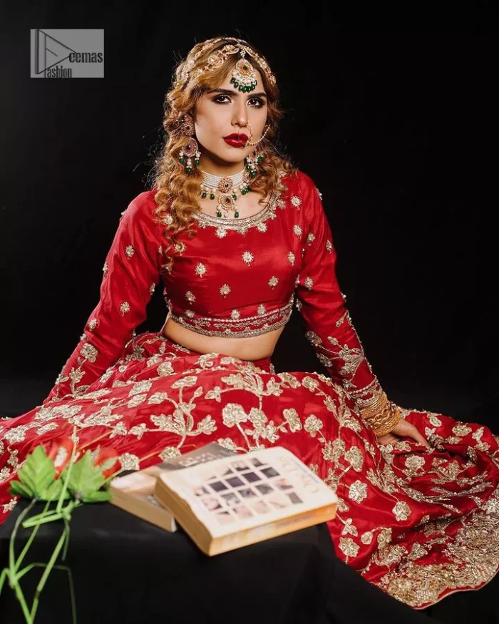 Reception called, and red answered. The stunning blouse is embellished with floral motifs. The base colour used for choli is wine red.  The sleeves of the blouse are embellished with floral patterns to make this reception wear the epitome of beauty. Further, the boat shape neckline also adds super charm and beauty when paired with a lehenga. The lehenga is adorned with golden embroidery which is further enhanced with tilla, dabka, kora, Kundan and the real magic of Zardozi. Complete this romantic article with a dupatta framed with a four-sided embellished border to give a glamorous touch to this magnificent attire.