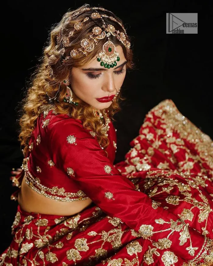 Reception called, and red answered. The stunning blouse is embellished with floral motifs. The base colour used for choli is wine red.  The sleeves of the blouse are embellished with floral patterns to make this reception wear the epitome of beauty. Further, the boat shape neckline also adds super charm and beauty when paired with a lehenga. The lehenga is adorned with golden embroidery which is further enhanced with tilla, dabka, kora, Kundan and the real magic of Zardozi. Complete this romantic article with a dupatta framed with a four-sided embellished border to give a glamorous touch to this magnificent attire.