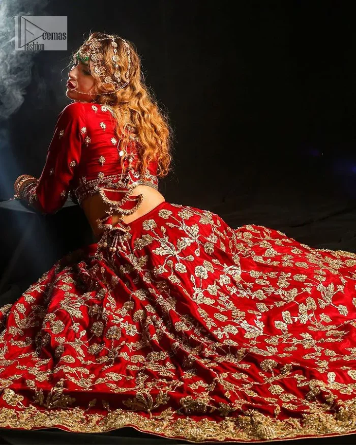 Reception called, and red answered. The stunning blouse is embellished with floral motifs. The base colour used for choli is wine red.  The sleeves of the blouse are embellished with floral patterns to make this reception wear the epitome of beauty. Further, the boat shape neckline also adds super charm and beauty when paired with a lehenga. The lehenga is adorned with golden embroidery which is further enhanced with tilla, dabka, kora, Kundan and the real magic of Zardozi. Complete this romantic article with a dupatta framed with a four-sided embellished border to give a glamorous touch to this magnificent attire.