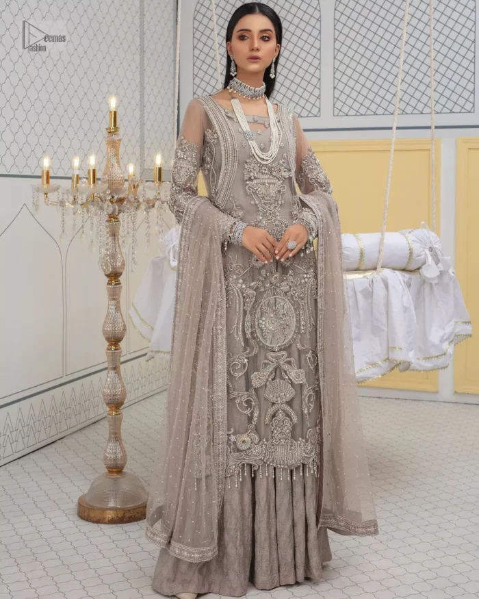 Chill vibes in grey are very rare. A beautiful grey shirt with a medley of hand-embellished floral motifs and floral patterns of silver embroidery which is highlighted with tilla, dabka, kora, Kundan and the real magic of Zardozi. The illusion neckline makes this party outfit a little romantic. Further, the floral patterns on full sleeves also add super beauty. It is paired up with plain jamawar trousers just to balance the look   Complete this gorgeous outfit with a dupatta in the same colour framed with four-sided borders and sequins sprayed all over. 