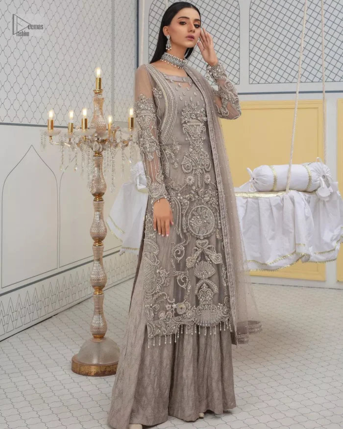 Chill vibes in grey are very rare. A beautiful grey shirt with a medley of hand-embellished floral motifs and floral patterns of silver embroidery which is highlighted with tilla, dabka, kora, Kundan and the real magic of Zardozi. The illusion neckline makes this party outfit a little romantic. Further, the floral patterns on full sleeves also add super beauty. It is paired up with plain jamawar trousers just to balance the look   Complete this gorgeous outfit with a dupatta in the same colour framed with four-sided borders and sequins sprayed all over. 