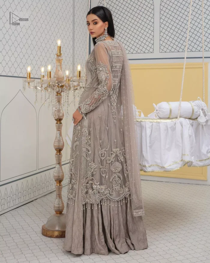 Chill vibes in grey are very rare. A beautiful grey shirt with a medley of hand-embellished floral motifs and floral patterns of silver embroidery which is highlighted with tilla, dabka, kora, Kundan and the real magic of Zardozi. The illusion neckline makes this party outfit a little romantic. Further, the floral patterns on full sleeves also add super beauty. It is paired up with plain jamawar trousers just to balance the look   Complete this gorgeous outfit with a dupatta in the same colour framed with four-sided borders and sequins sprayed all over. 
