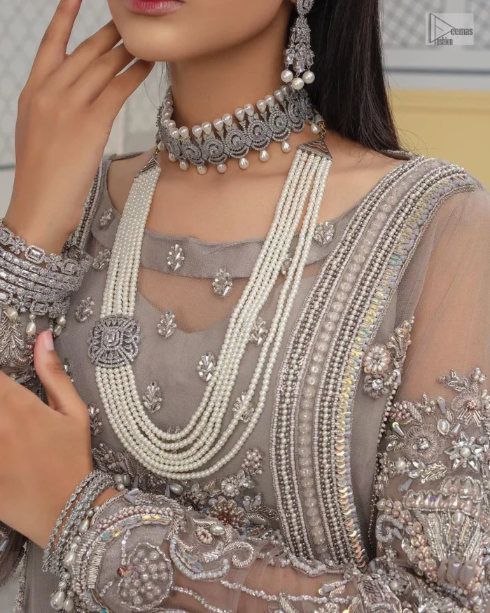 Chill vibes in grey are very rare. A beautiful grey shirt with a medley of hand-embellished floral motifs and floral patterns of silver embroidery which is highlighted with tilla, dabka, kora, Kundan and the real magic of Zardozi. The illusion neckline makes this party outfit a little romantic. Further, the floral patterns on full sleeves also add super beauty. It is paired up with plain jamawar trousers just to balance the look   Complete this gorgeous outfit with a dupatta in the same colour framed with four-sided borders and sequins sprayed all over. 