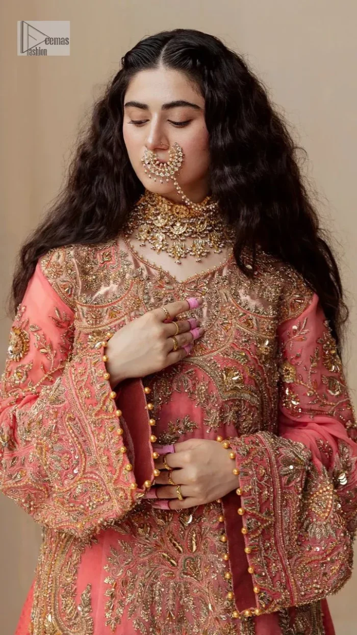It's an aesthetic kinda mood. The long shirt in the wondrous peach colour is composed of ethnic handworked details and gleaming embellishments rendered artistically on a Jamawar canvas. The long shirt is layered with embroidered details with an enhanced V neckline and borders. The beautiful shirt is prominent with tilla, dabka, kora, Kundan and Zardozi in gold colour. Further, the intricate floral patterns on full sleeves make this outfit crazier. Complementing the shirt with gharara with elaborated borders depicts a perfect contemporary vibe.