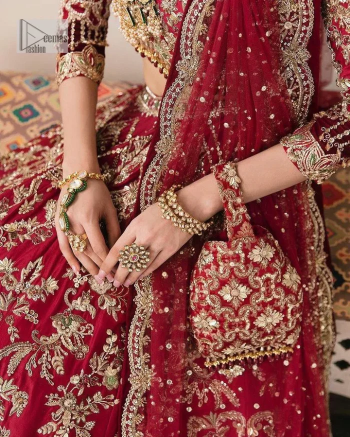 The beauty of this ensemble is mirrored in the romantic colour palette! The blouse is in a dark red shade and is fully decorated with intricate designs and fine details of goldwork. Lavish embroidery, tilla,dabka, kora, Kundan, gold, and zari work make this reception outfit a charismatic masterpiece. The boat shape neckline on a scalloped blouse gives the gorgeous Bride a head-turning look. In addition to this, the three-quarter sleeves for a more upscale appearance and feel. It is systemized with a lehenga in the same colour adorned with heavy floral patterns that are essential for your dreamy look. Complete this romantic look with a dupatta framed with four-sided embellished borders and sequins sprayed all over. Still, thinking? This is a no-brainer. Get your hands on this one ASAP before it sells out!