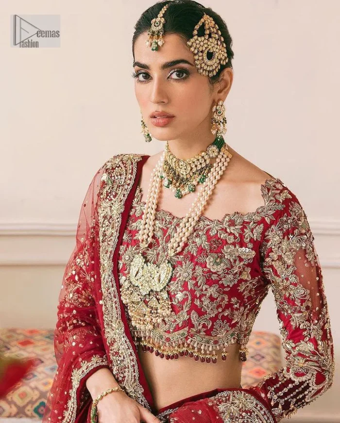 The beauty of this ensemble is mirrored in the romantic colour palette! The blouse is in a dark red shade and is fully decorated with intricate designs and fine details of goldwork. Lavish embroidery, tilla,dabka, kora, Kundan, gold, and zari work make this reception outfit a charismatic masterpiece. The boat shape neckline on a scalloped blouse gives the gorgeous Bride a head-turning look. In addition to this, the three-quarter sleeves for a more upscale appearance and feel. It is systemized with a lehenga in the same colour adorned with heavy floral patterns that are essential for your dreamy look. Complete this romantic look with a dupatta framed with four-sided embellished borders and sequins sprayed all over. Still, thinking? This is a no-brainer. Get your hands on this one ASAP before it sells out!