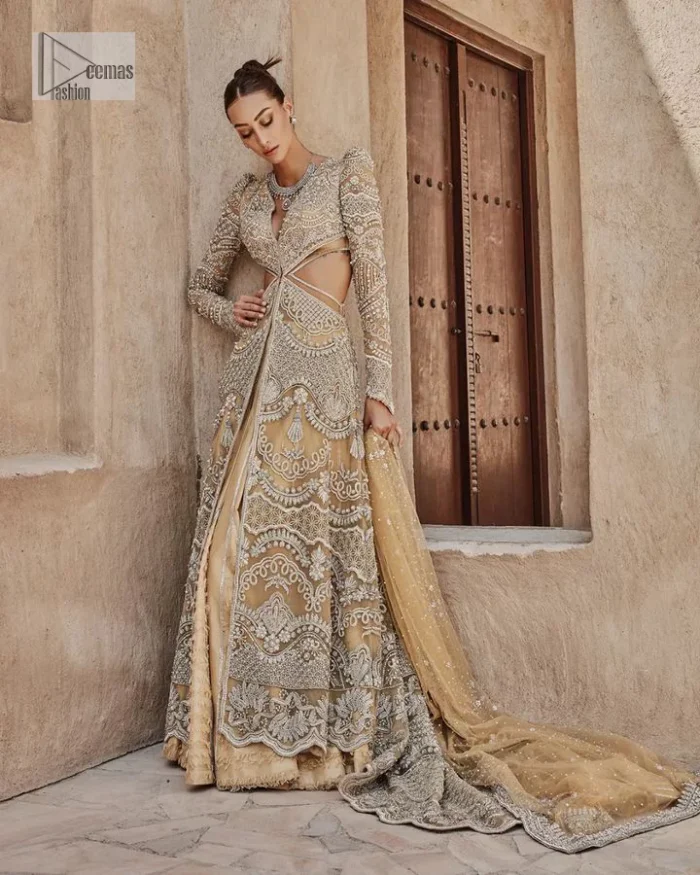 Bold, edgy, and wrapped in glamour. A sumptuous palette of gold with silver delicate embroidery, signature handcrafted embellishment includes tilla, dabka, kora, Kundan, Zardozi and crystals. Take your look to the next level with this golden front open gown which has V shape neckline and full sleeves. The floral patterns on the following gown just steal everyone's heart on your big day. It is paired up with a lehenga to enhance the beauty of this nikah outfit. Complete this article with a dupatta framed with four-sided embellished borders and sequins sprayed all over to wrap you in a bold outfit.