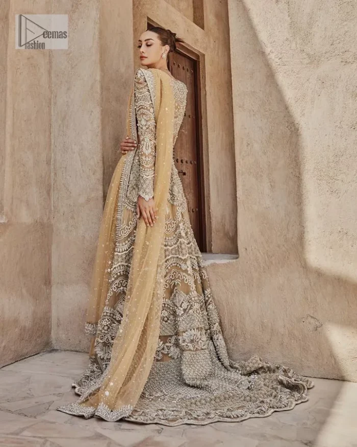 Bold, edgy, and wrapped in glamour. A sumptuous palette of gold with silver delicate embroidery, signature handcrafted embellishment includes tilla, dabka, kora, Kundan, Zardozi and crystals. Take your look to the next level with this golden front open gown which has V shape neckline and full sleeves. The floral patterns on the following gown just steal everyone's heart on your big day. It is paired up with a lehenga to enhance the beauty of this nikah outfit. Complete this article with a dupatta framed with four-sided embellished borders and sequins sprayed all over to wrap you in a bold outfit.