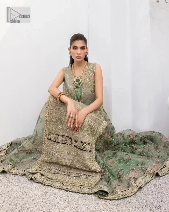 The timelessly classic mint green nikah outfit! The beautiful model looks ravishing in this mint green shirt, heavily hand-embellished with floral motifs and sequins spray. The back of the shirt is sprayed with sequins and has an embellished border; an embellished front and back panel border makes this outfit unique. The V shape neckline adds super beauty to the outfit which involves tilla, dabka, kora, Kundan and the real magic of crystals. Further, the sleeveless style is for extra comfort zone. It is paired with a flared lehenga with an intricately embellished border. 