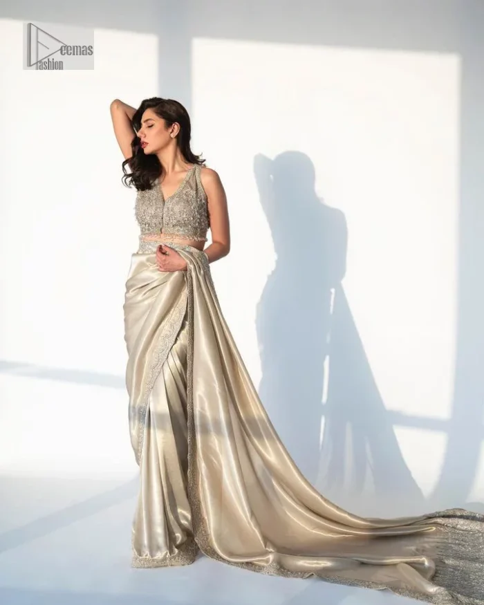 It's an aesthetic kinda mood. A silver blouse hand embellished with dabka, naqshi, cut dana, Resham, tilla, kora, sequin and Kundan. A heavily embellished blouse featuring floral patterns encompassing a breathtaking keyhole and vertical embellishments along the strips of the back flare. The V shape neckline of the blouse looks divine when comes with a sleeveless style. It is paired with a scalloped saree with an embellished border and the pallu is decorated with silver embroidery to make this Nikah outfit lovely and charming. 