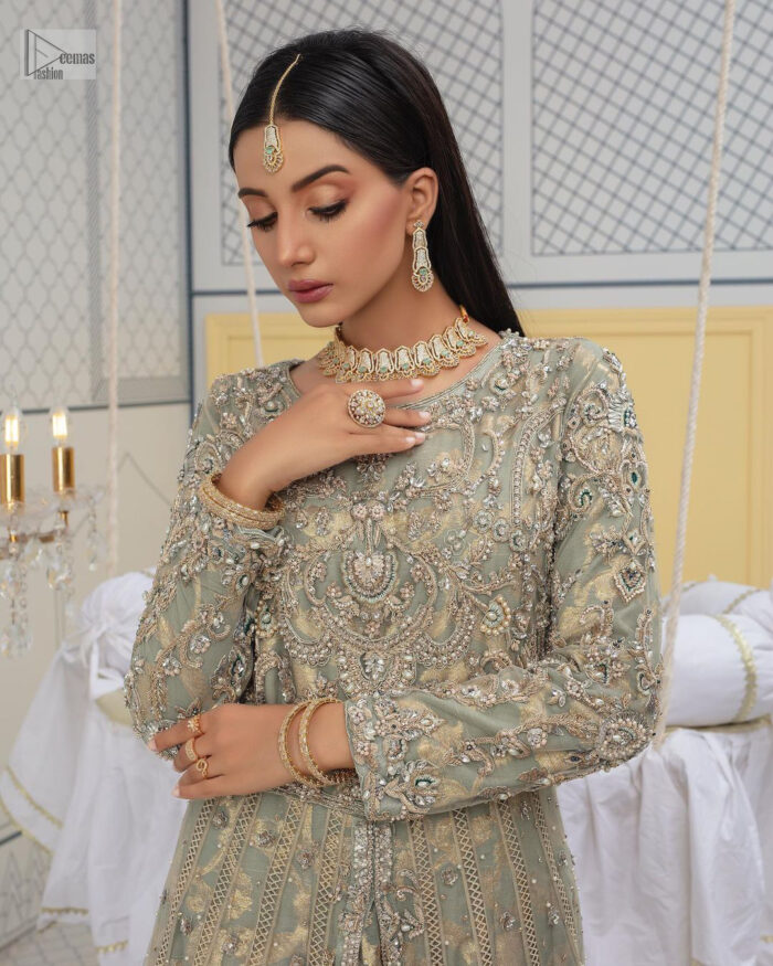 Embellishment is on the rise! The elegant front open maxi is heavily embellished in work of tilla, sequins, dabka, Zardozi, Kundan and kora work. The magnificent maxi is further highlighted with silver embroidery on the front and backside. Further, the full sleeves of the dress come with attractive embellishments. The round neckline makes this masterpiece more unique and charming. This nikah outfit is coordinated with a dupatta in teal green colour framed with a four-sided border and sparkling sequins all over that are on the peak in modern style.